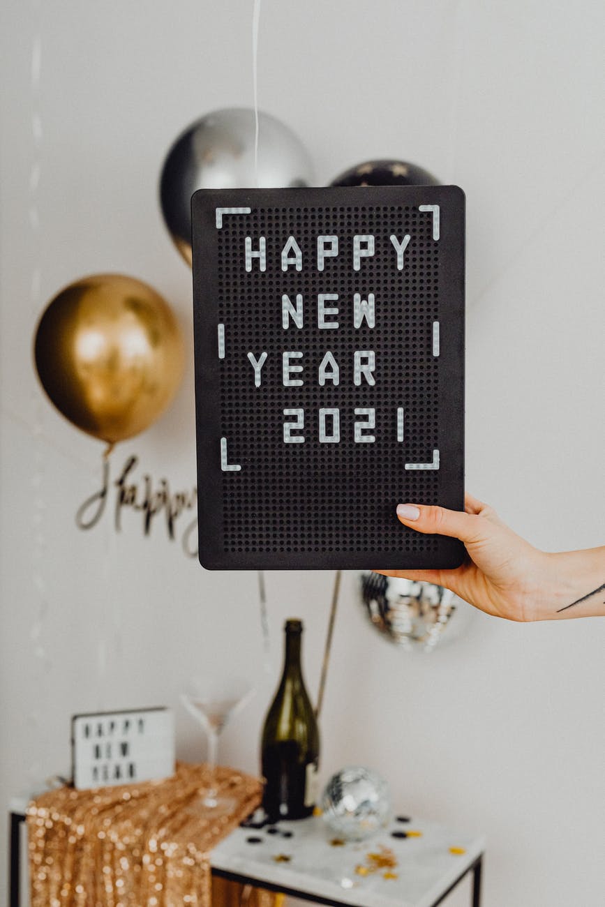 person holding a happy new year text on a black board